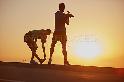 Buy stock photo Shot of a silhouetted couple out for a run at sunrise