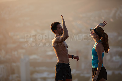 Buy stock photo Shot of an athletic young couple exercising above the city in the morning