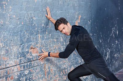 Buy stock photo Shot of a focussed young man working out next to a brick wall outside