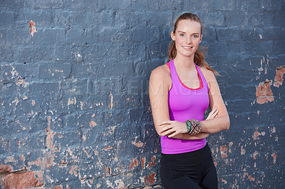 Buy stock photo Portrait of a happy young woman working out next to a brick wall outside