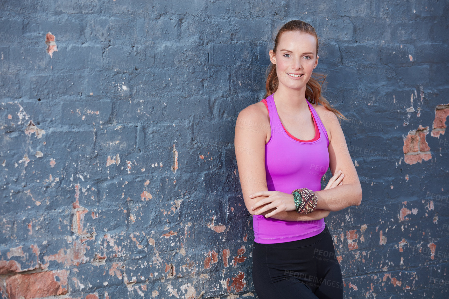 Buy stock photo Portrait of a happy young woman working out next to a brick wall outside