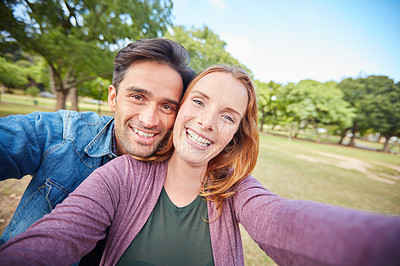 Buy stock photo Portrait of a young couple taking a selfie while out at the park