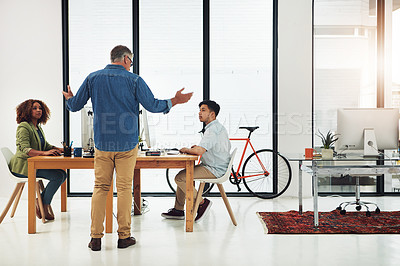Buy stock photo Shot of a mature businessman addressing two employees in the office