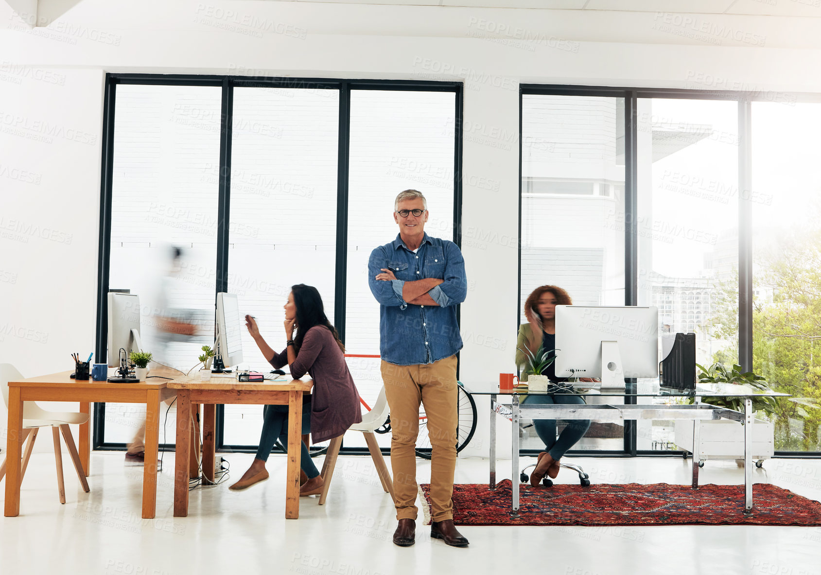 Buy stock photo Portrait of a mature designer standing in the office with his colleagues in the background