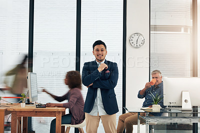 Buy stock photo Portrait of a young designer standing in the office with his colleagues in the background