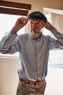 Buy stock photo Portrait of a cheerful senior man trying on one of his hats while looking at the camera