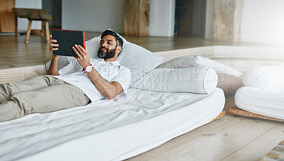 Buy stock photo Shot of a easygoing bachelor using his tablet while relaxing on the couch at home