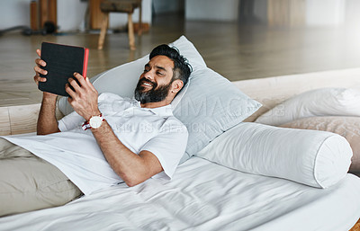 Buy stock photo Shot of a easygoing bachelor using his tablet while relaxing on the couch at home