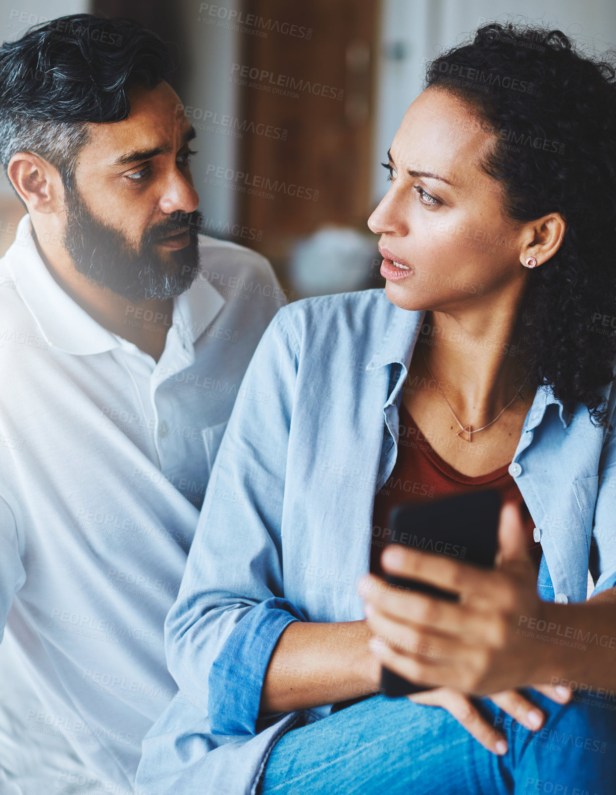 Buy stock photo Shot of a dismayed couple receiving bad news via a smartphone at home