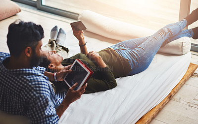Buy stock photo Shot of a laid-back couple relaxing with wireless technology at home