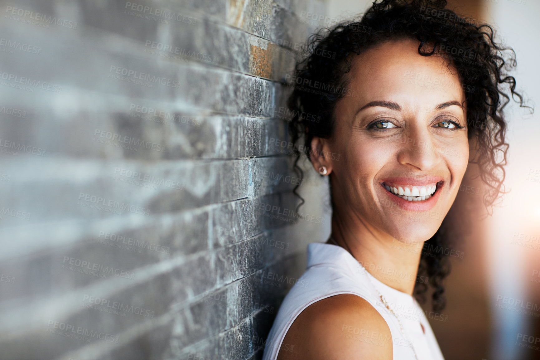 Buy stock photo Portrait of a happy woman posing against a brick wall at home