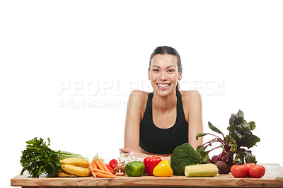 Buy stock photo Studio portrait of an attractive young woman posing with a table full of vegetables against a white background