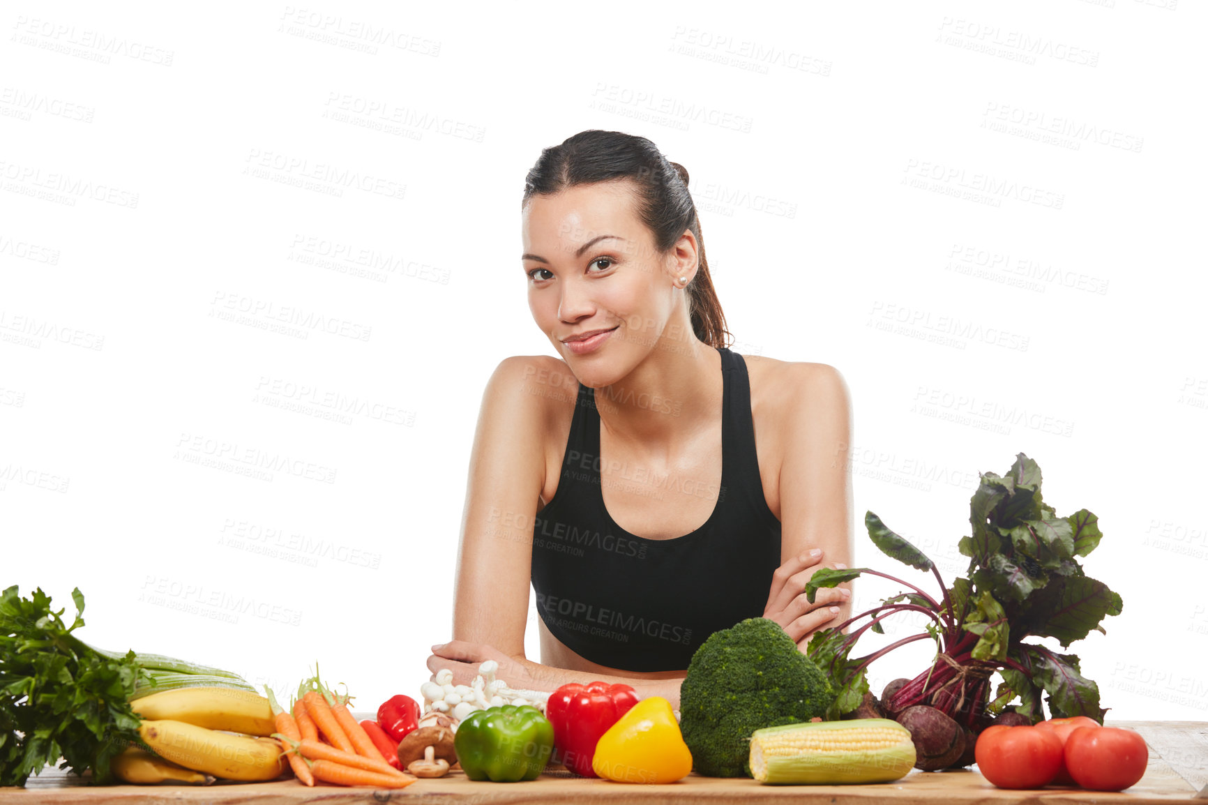 Buy stock photo Studio portrait of an attractive young woman posing with a table full of vegetables against a white background