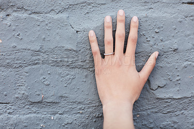 Buy stock photo Hand of a woman wearing a ring on her finger. Closeup of a woman announcing her engagement against a grey painted wall with copyspace. Manicured nails and jewelry. Single wedding band for proposal
