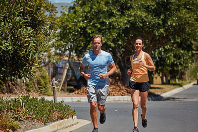 Buy stock photo Shot of a happy couple jogging together in their neighborhood