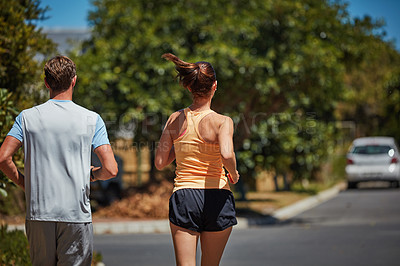 Buy stock photo Rearview shot of an unidentifiable couple jogging together in their neighborhood