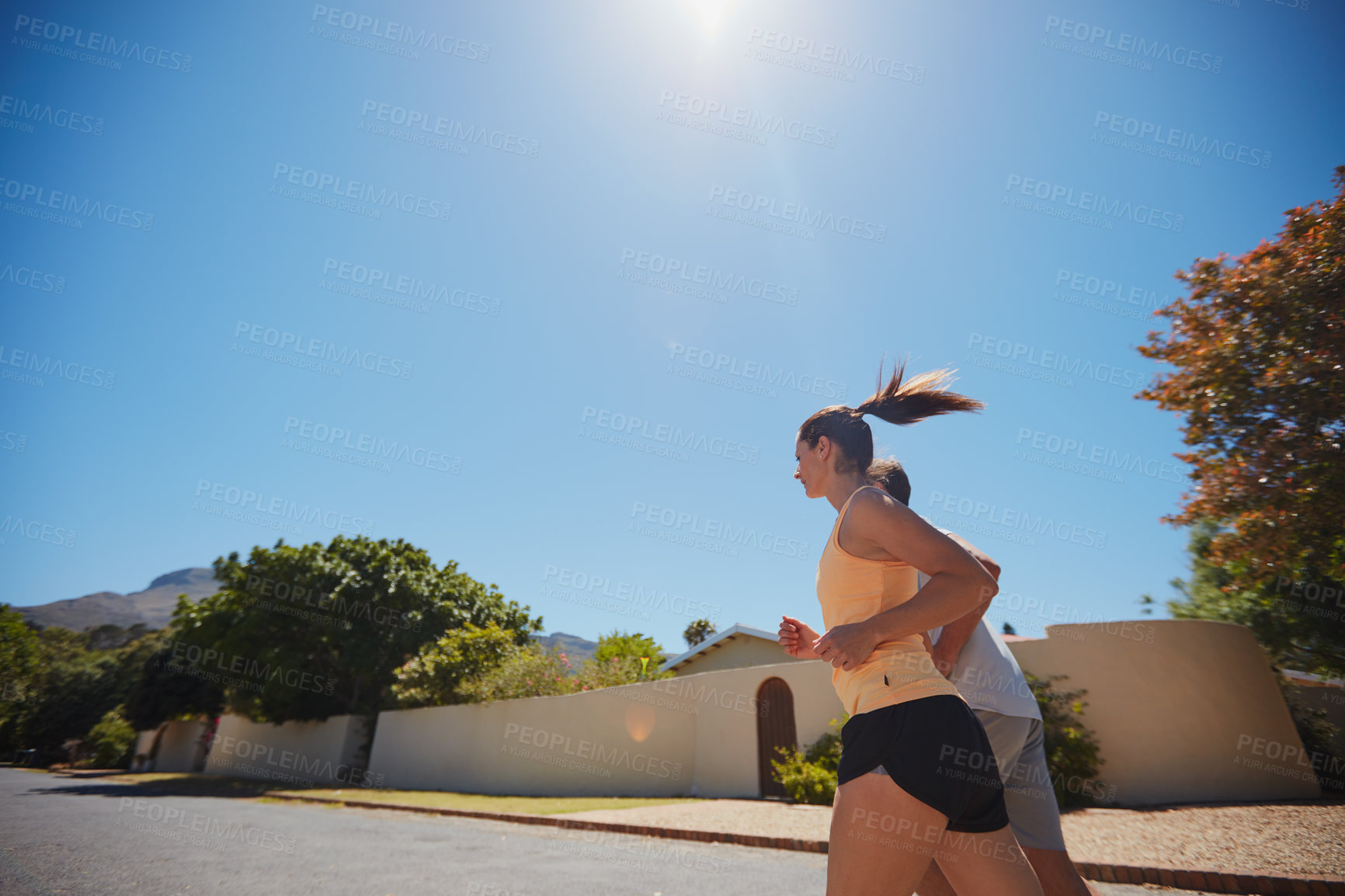 Buy stock photo Low angle shot of a happy couple jogging together in their neighborhood