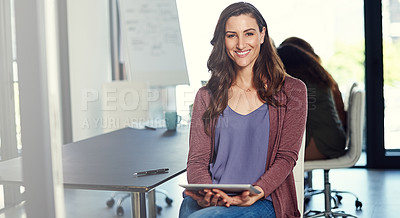 Buy stock photo Portrait of a young businesswoman working on a digital tablet with her colleagues in the background