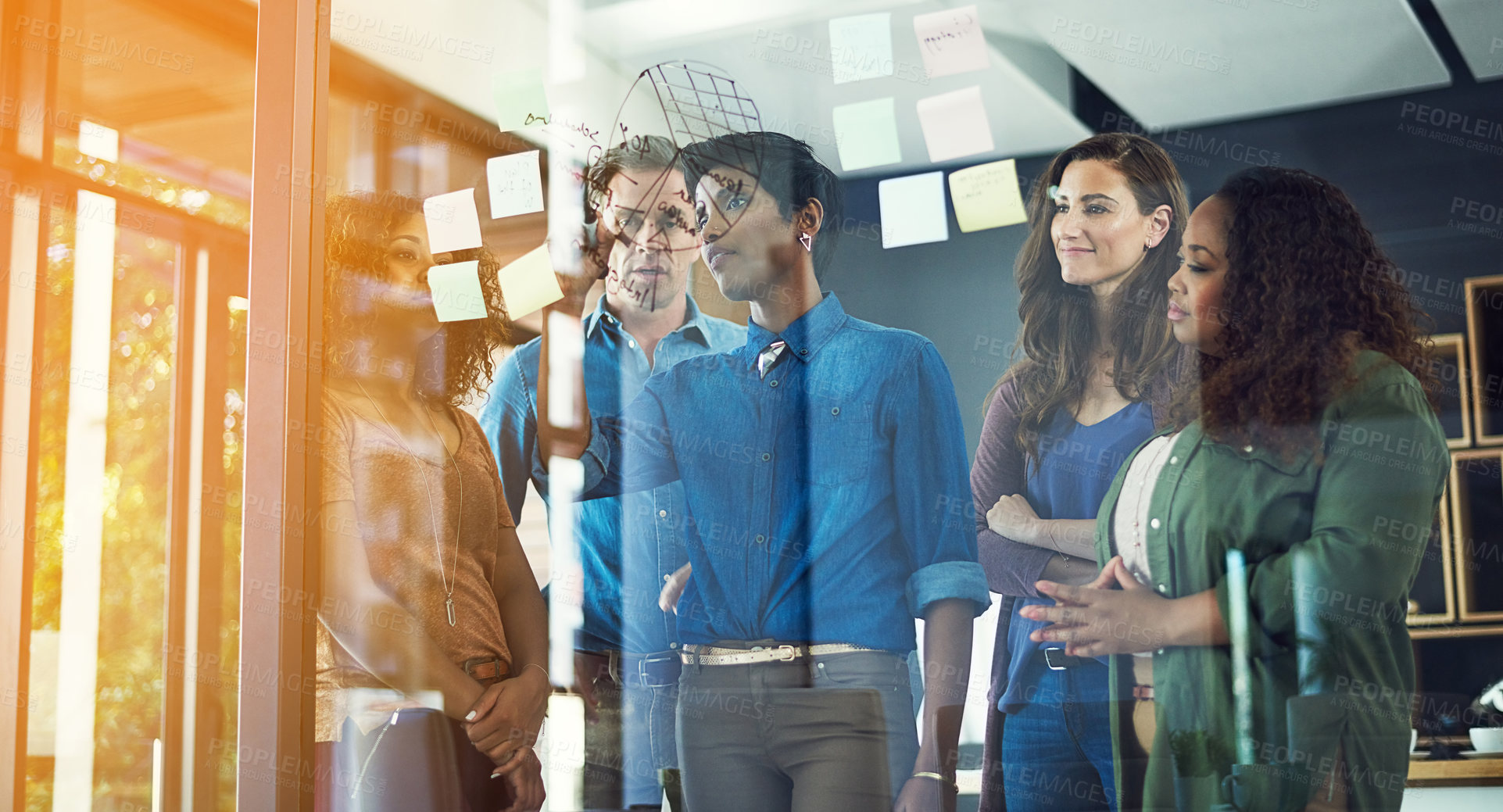 Buy stock photo Cropped shot of a group of businesspeople brainstorming with notes on a glass wall in an office