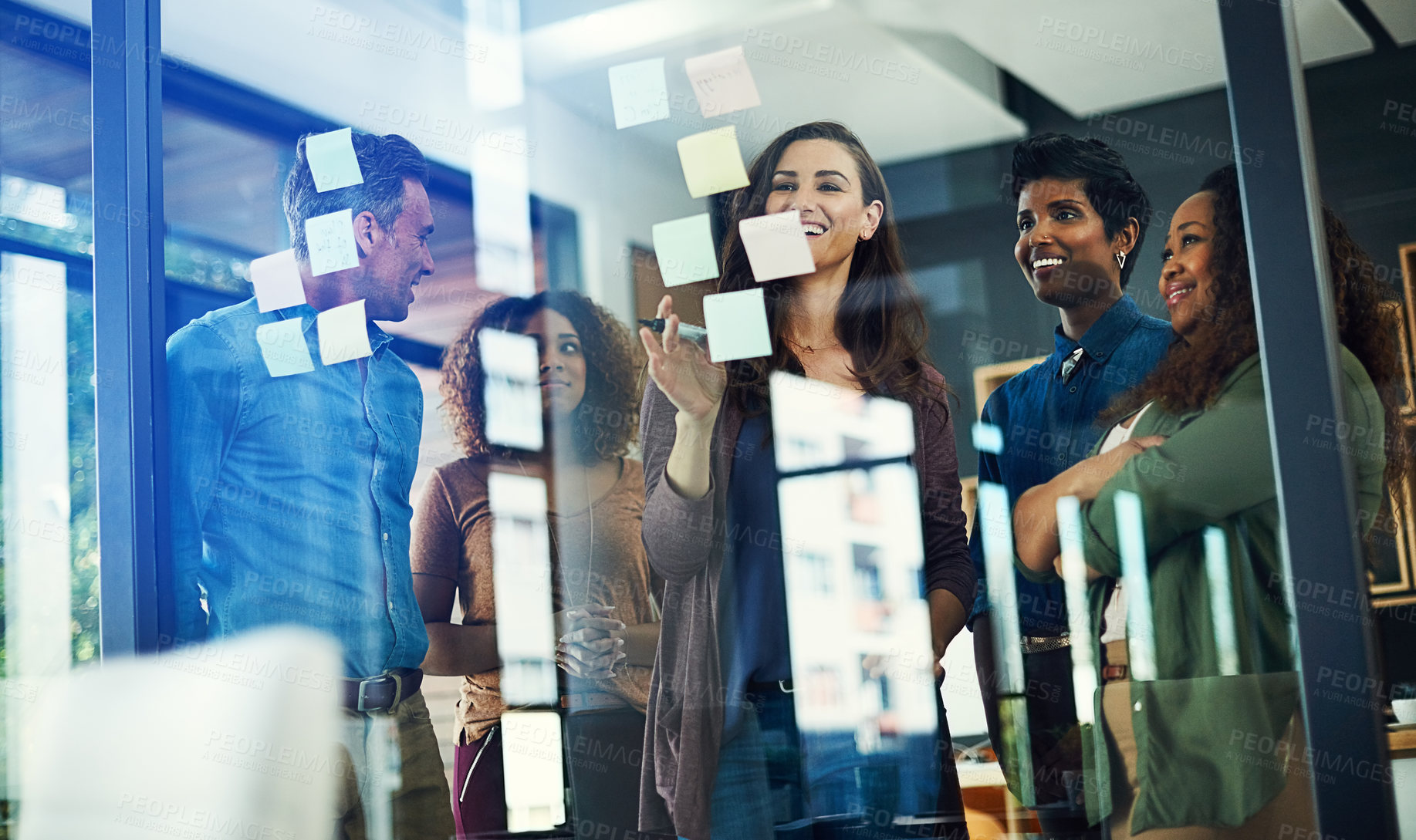 Buy stock photo Cropped shot of a group of businesspeople brainstorming with notes on a glass wall in an office