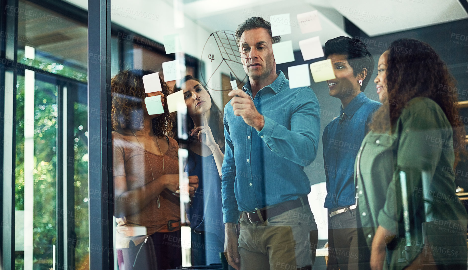 Buy stock photo Cropped shot of a group of businesspeople brainstorming with notes on a glass wall in an office