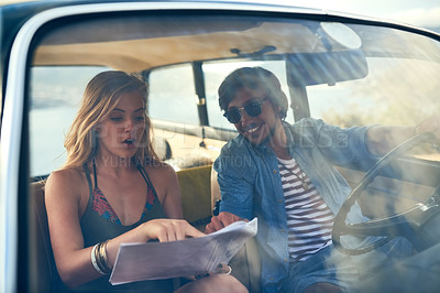 Buy stock photo Cropped shot of an affectionate young couple looking at a map during their roadtrip