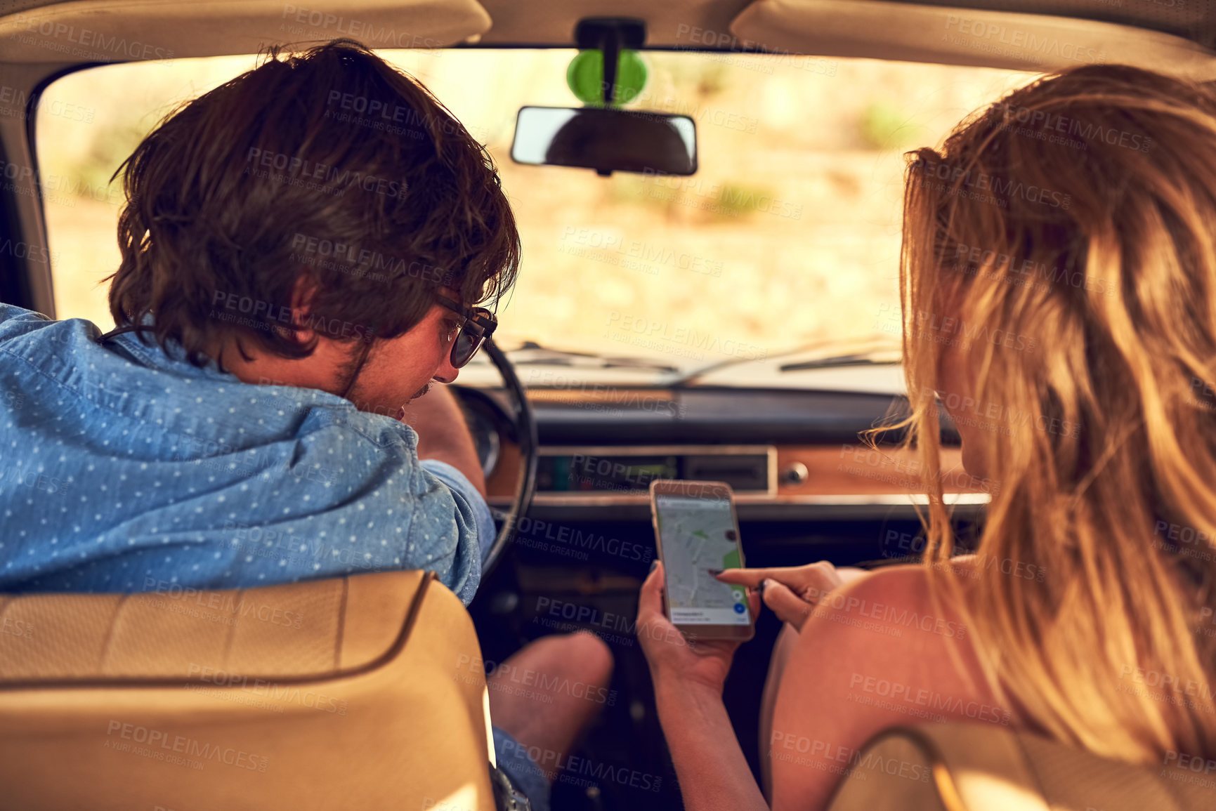 Buy stock photo Rearview shot of an affectionate young couple following their gps during a roadtrip