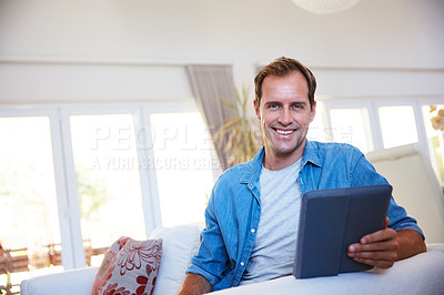 Buy stock photo Portrait of a man using a digital tablet and relaxing on the sofa at home