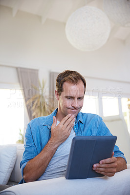 Buy stock photo Shot of a man looking uncertain while using a digital tablet at home