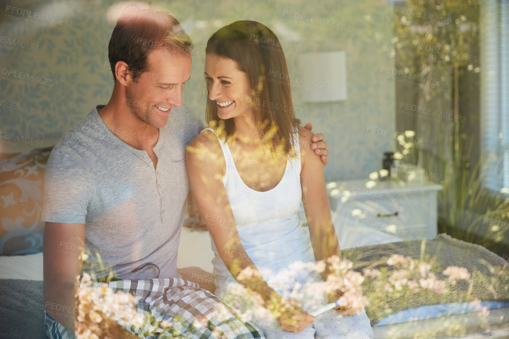 Buy stock photo Happy, pregnancy test and couple in bedroom by window excited for results, fertility news and ivf success. Pregnant, parenting and man with woman with stick for future family, bonding and love on bed