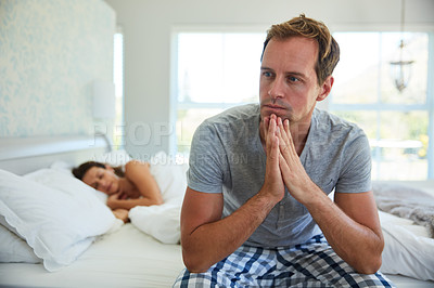 Buy stock photo Shot of a man looking worried while his wife sleeps in the background
