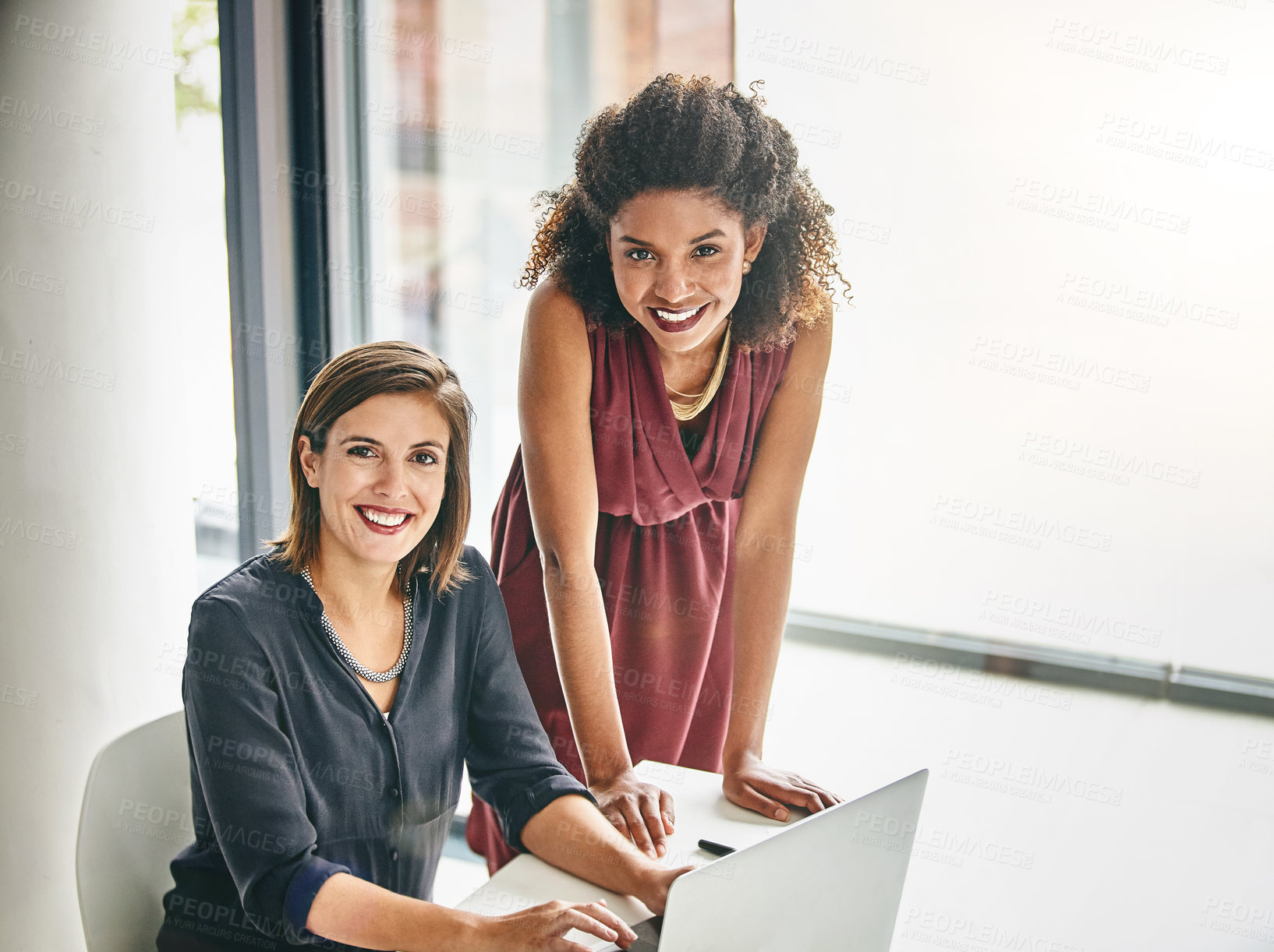 Buy stock photo Portrait of two businesswomen working together on a laptop in an office