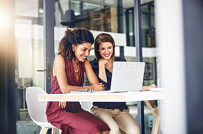 Buy stock photo Cropped shot of two young businesswomen using a laptop in an office