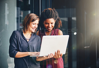 Buy stock photo Cropped shot of two young businesswomen using a laptop outside an office