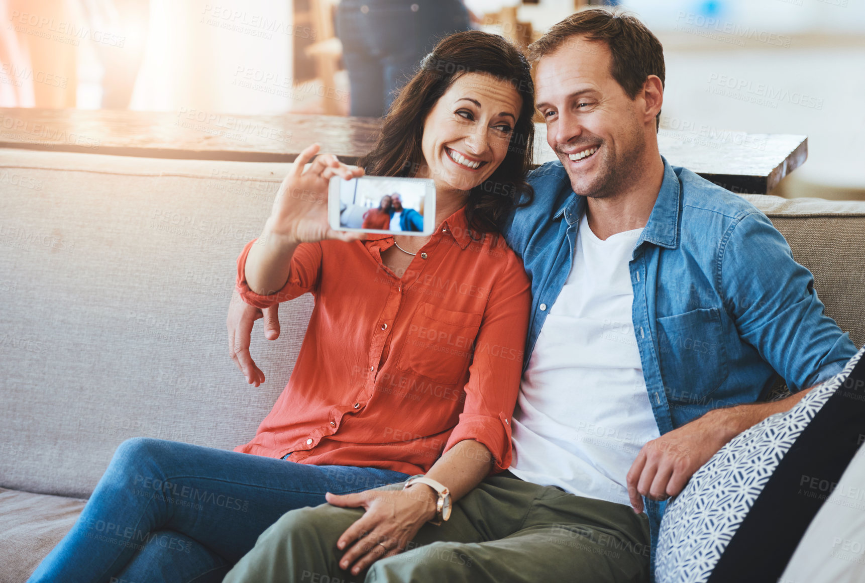 Buy stock photo Cropped of an affectionate couple taking selfies on the sofa at home