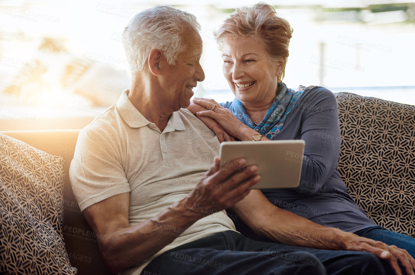 Buy stock photo Shot of a happy senior couple using a digital tablet together on the sofa at home