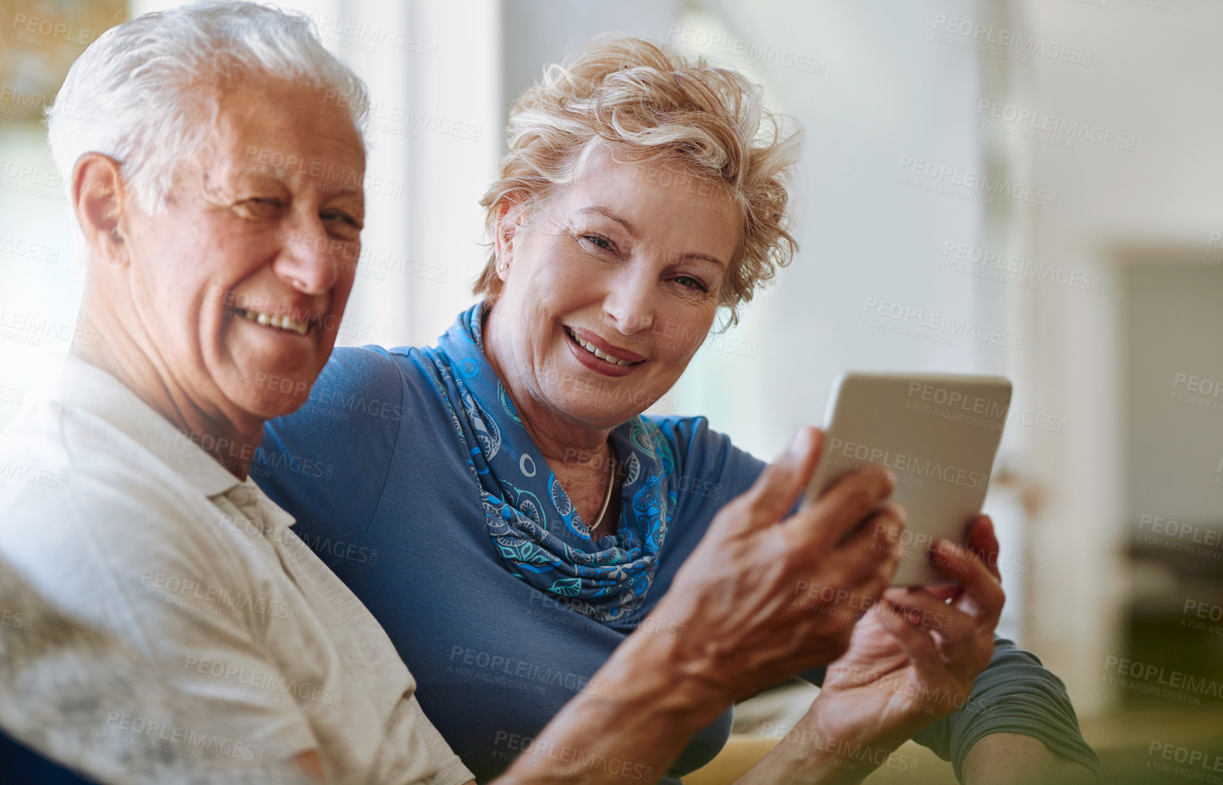 Buy stock photo Portrait of a happy senior couple using a digital tablet together on the sofa at home