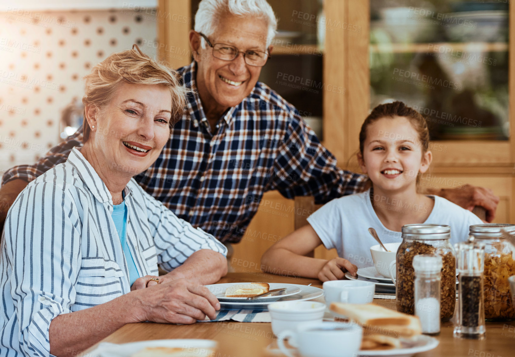 Buy stock photo Portrait of a little girl having breakfast with her grandparents at home