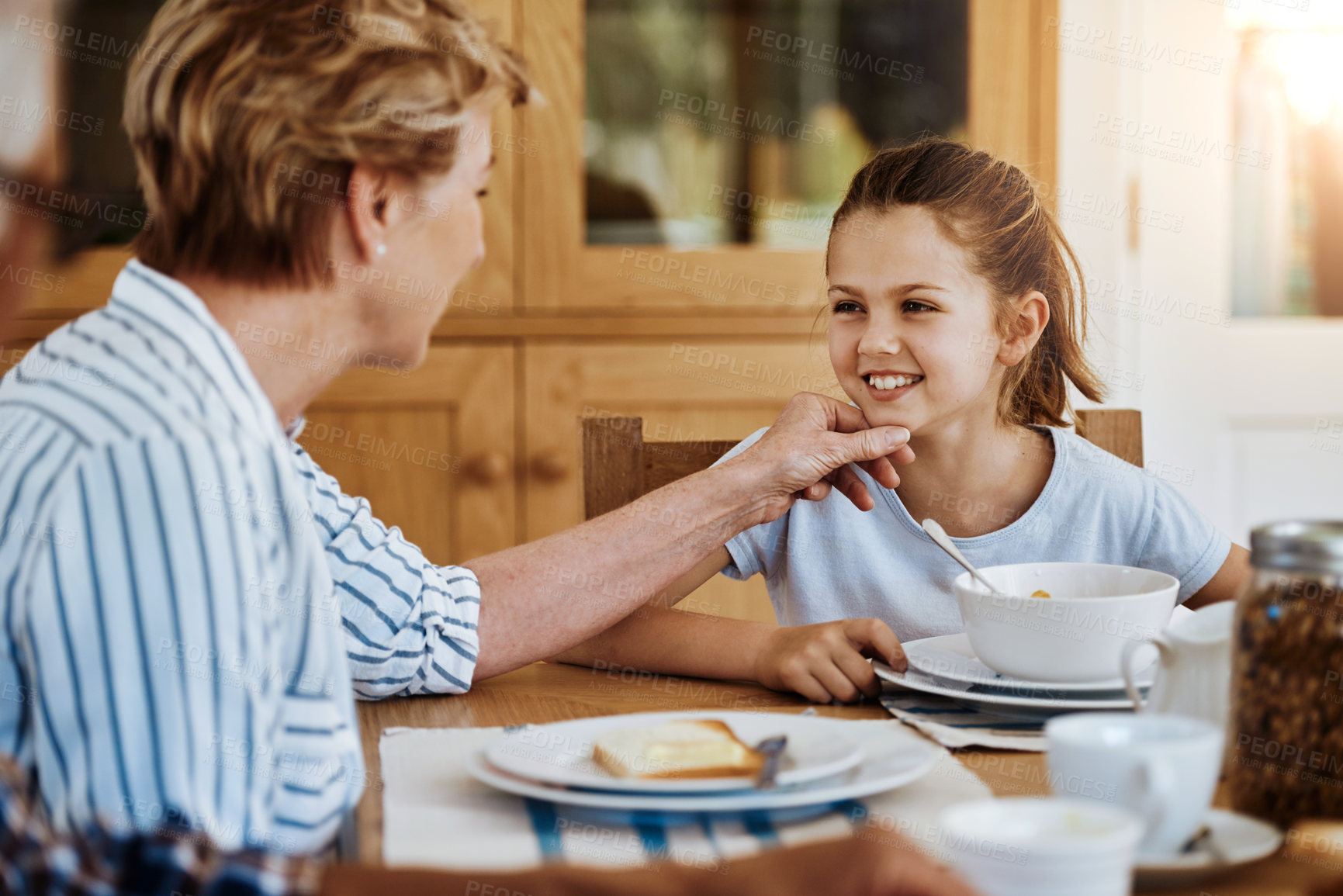 Buy stock photo Cropped shot of a little girl having breakfast with her grandmother at home
