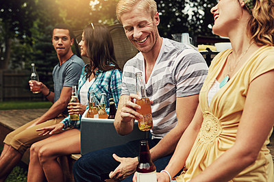 Buy stock photo Shot of a young man chatting to a friend at a party outdoors