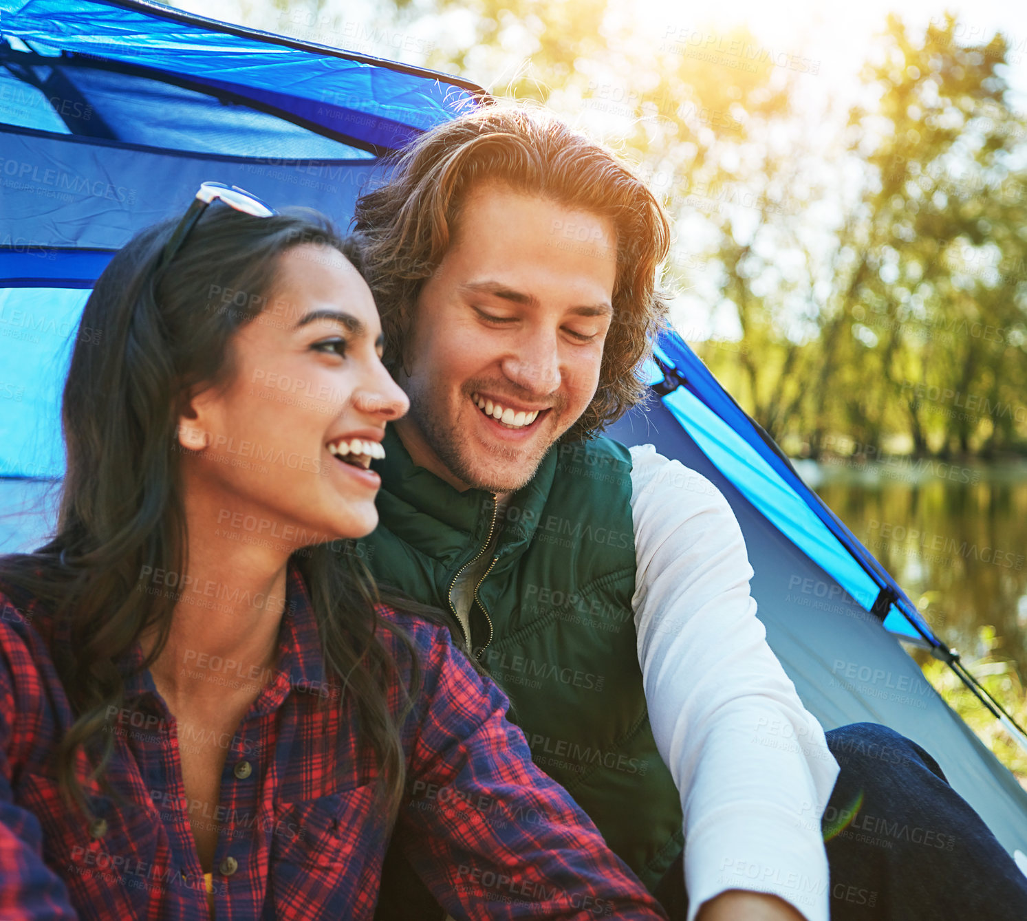 Buy stock photo Camping, couple and relax in tent laughing with love and happiness together on adventure in woods. People, embrace or outdoor journey in nature and funny chat on vacation or travel to river in forest