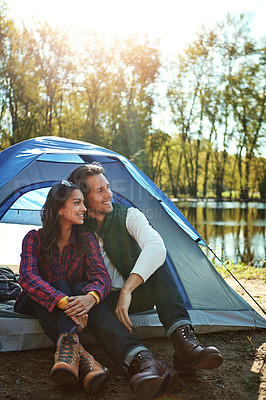 Buy stock photo Camping, tent and couple relax in woods with love and happiness together on adventure. People, smile and thinking of journey in nature with chat on holiday, vacation or travel in forest at river