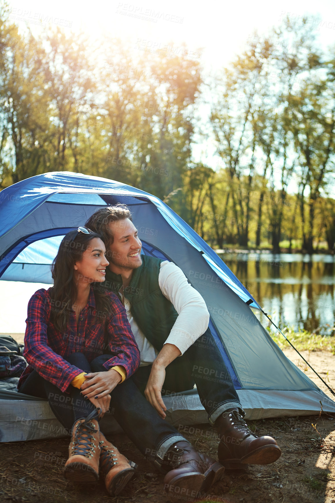 Buy stock photo Camping, tent and couple relax in woods with love and happiness together on adventure. People, smile and thinking of journey in nature with chat on holiday, vacation or travel in forest at river