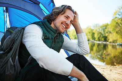 Buy stock photo Cropped shot of a handsome young man sitting at his campsite