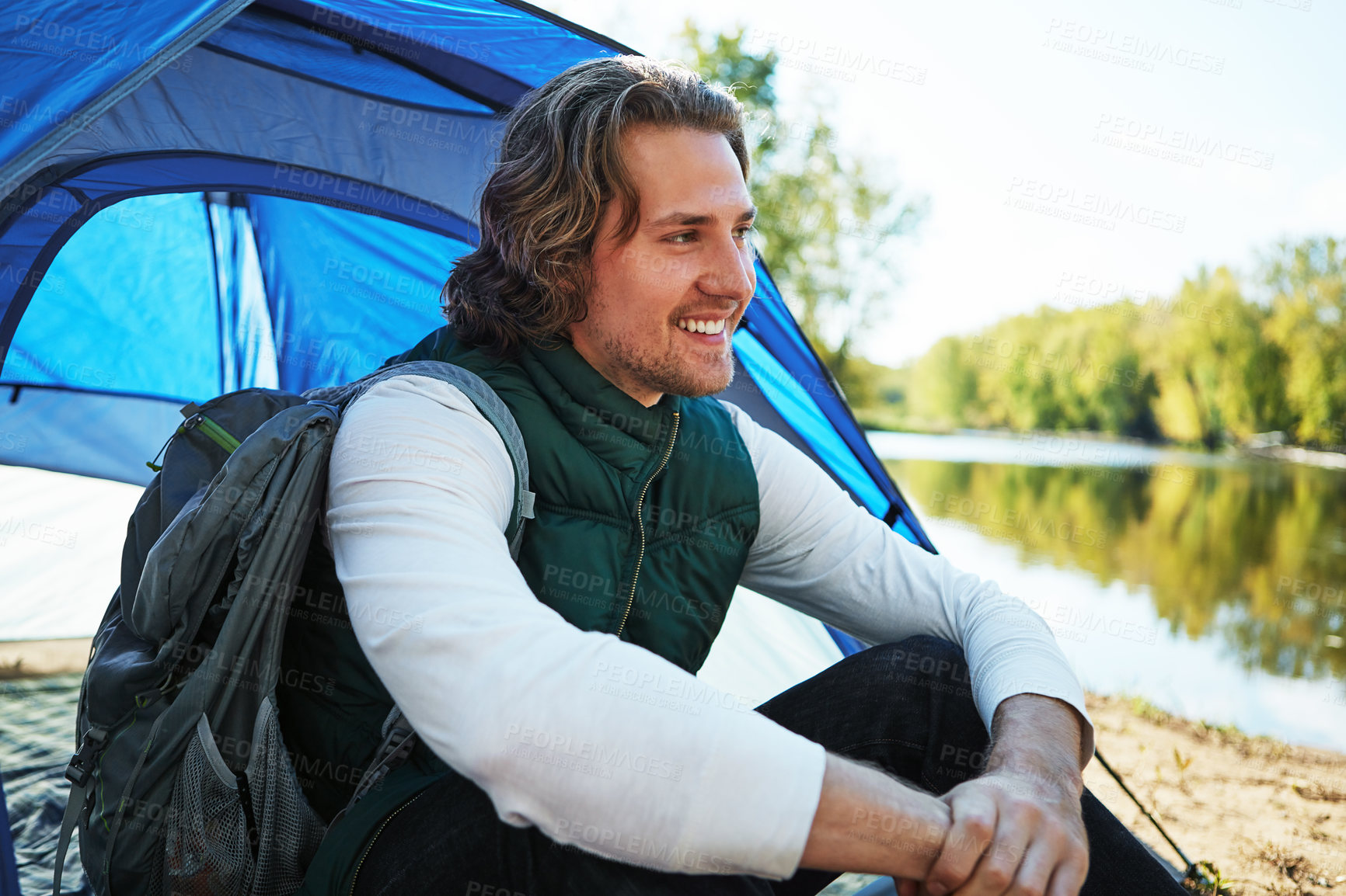 Buy stock photo Cropped shot of a handsome young man sitting at his campsite