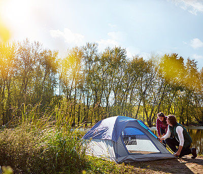 Buy stock photo Shot of an adventurous setting up their tent by the lake