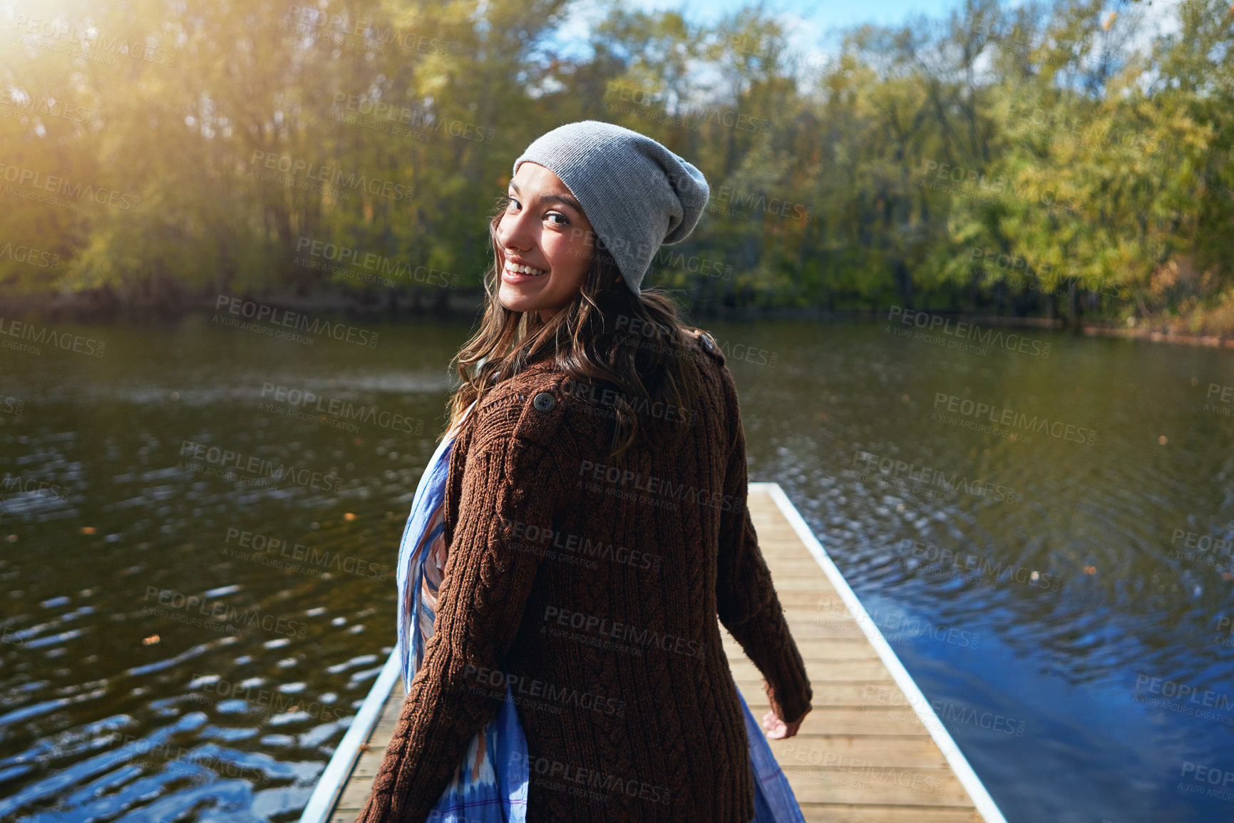 Buy stock photo Portrait of a happy young woman standing on a pier next to a lake