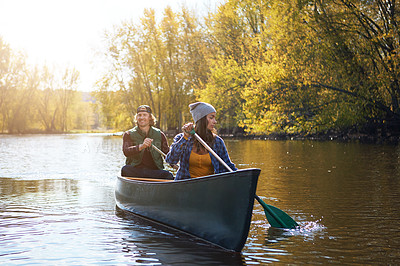 Buy stock photo Shot of a young couple going for a canoe ride on the lake