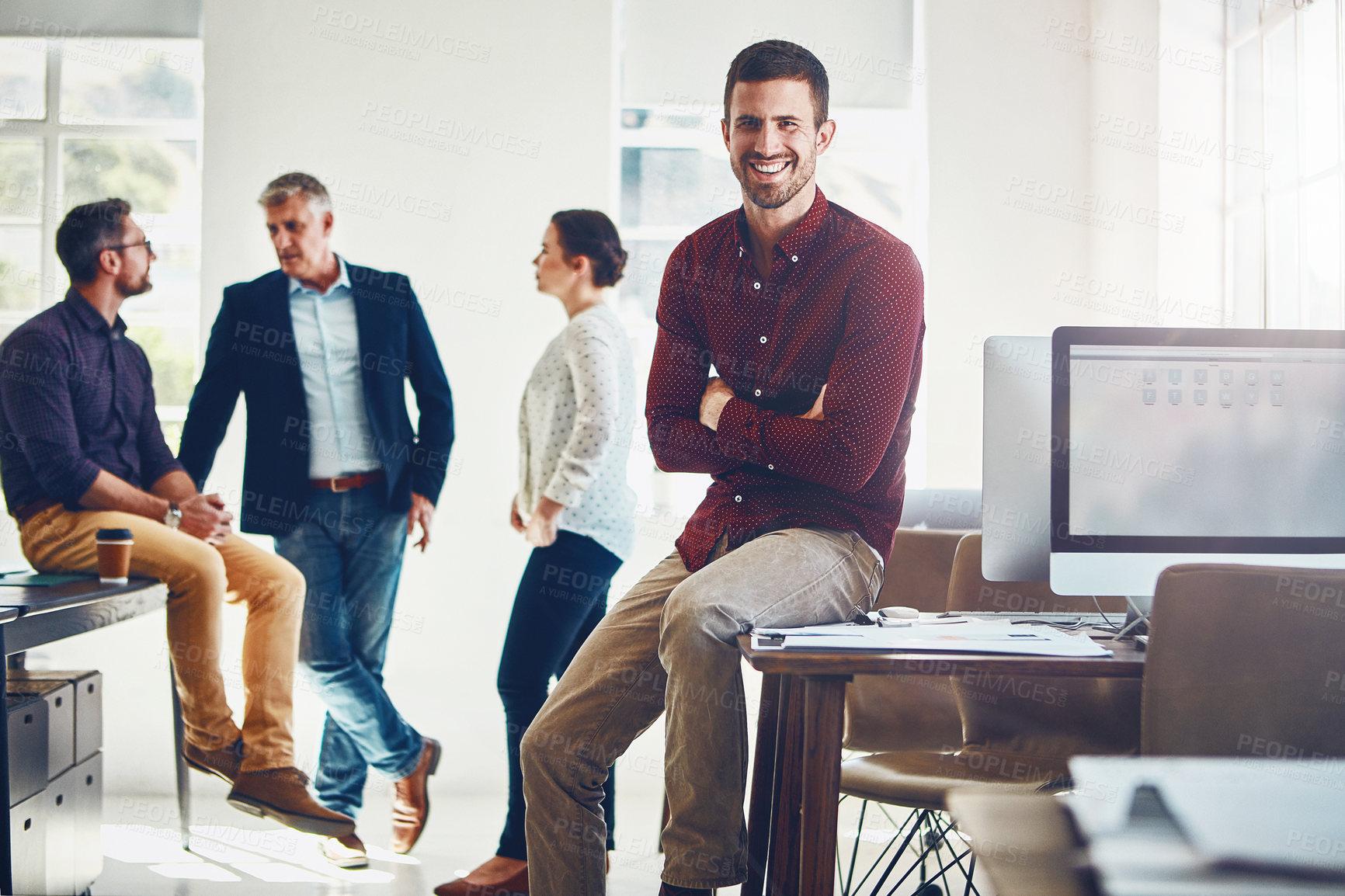 Buy stock photo Portrait of a young man with his colleagues having a discussion in the background