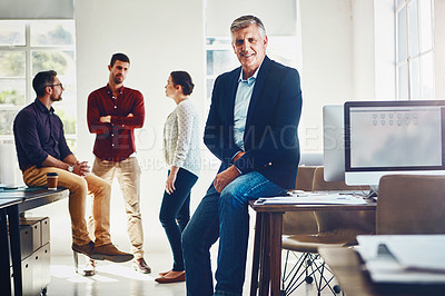 Buy stock photo Portrait of a mature man posing while his colleagues stand in the background